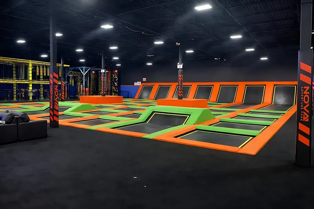 Large indoor trampoline court with orange and green padded frames
